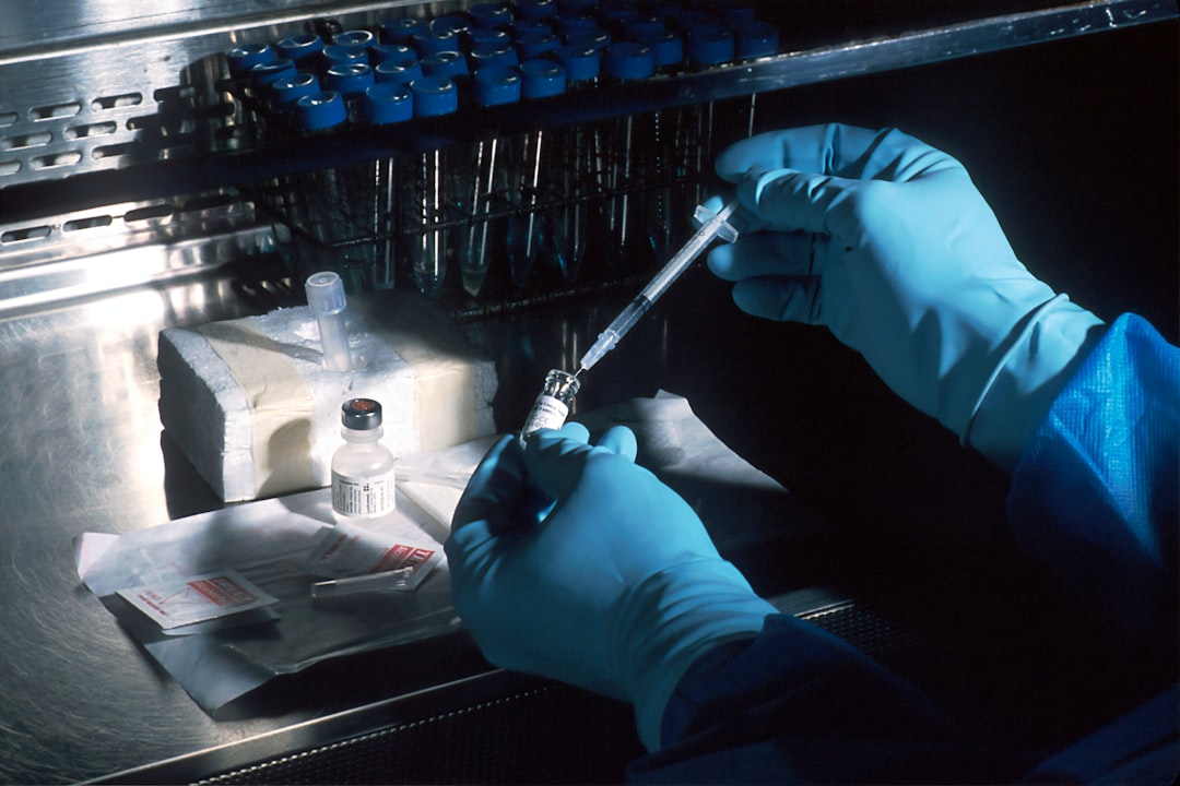 gloved hands drawing vaccine from vial with syringe